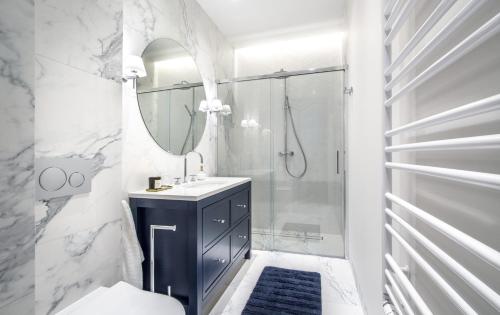 a white bathroom with a sink and a shower at Nowa Motława/Victoriapartments in Gdańsk