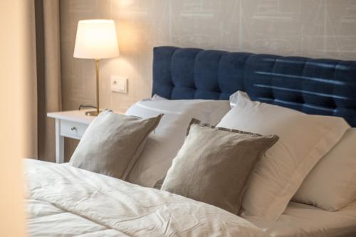 a bed with white pillows and a blue headboard at Nowa Motława/Victoriapartments in Gdańsk