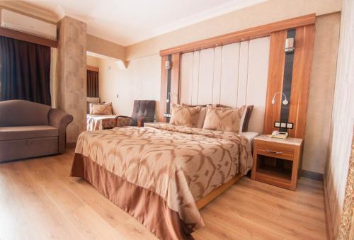 a hotel room with a large bed and a chair at LAUR HOTELS Experience & Elegance in Didim