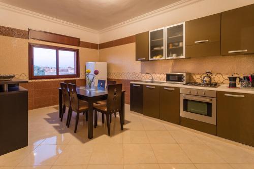 a kitchen with a table and chairs and a refrigerator at Résidence Bab El Janoub in Ouarzazate