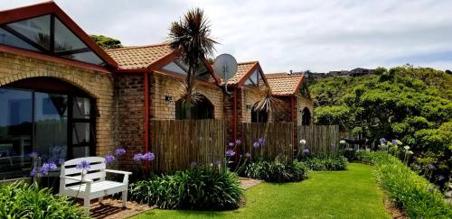 a house with a fence and a white bench in a yard at Dutton's Cove Guest House in Herolds Bay