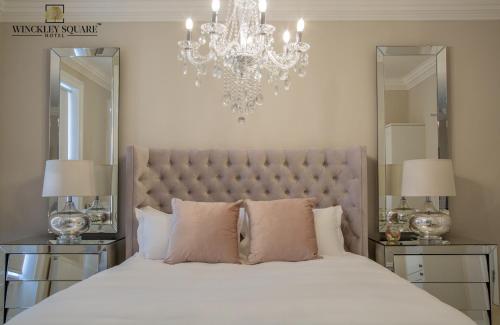sypialnia z dużym białym łóżkiem z żyrandolem w obiekcie Winckley Stays w mieście Preston
