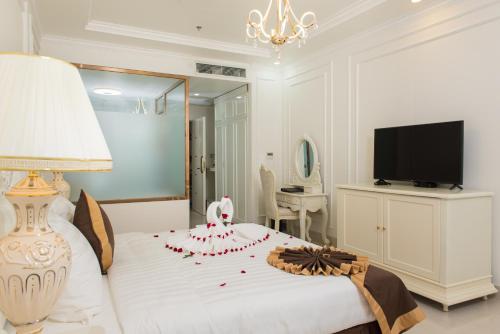 a bedroom with a white bed with a dresser and a television at Canh Hung Palace in Hai Phong