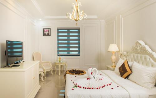 a white bedroom with a white bed and a television at Canh Hung Palace in Hai Phong