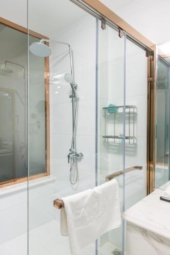 a glass shower with a white chair in a bathroom at Canh Hung Palace in Hai Phong