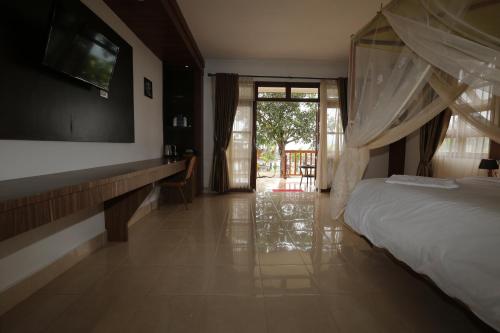 a bedroom with a bed and a tv on a wall at Toba Village Inn in Tuk Tuk