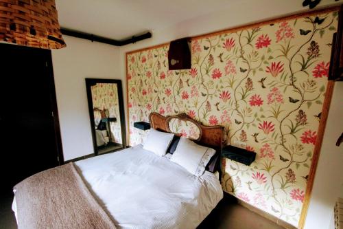 1 dormitorio con 1 cama y papel pintado con motivos florales en Loboratorio Rural, La Casa de al Lado, en Casas del Abad