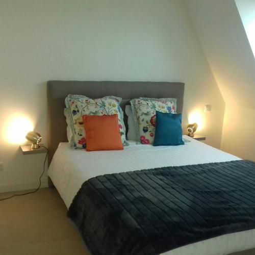 um quarto com uma cama grande e almofadas coloridas em Balcon avec vue panoramique de la mer, le village et la campagne - parking privé em Wimereux