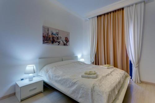 a white bedroom with a bed with two towels on it at Central Apartment in St Julian's, Perfect for Families in St. Julianʼs