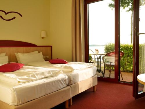 Dos camas en una habitación de hotel con balcón. en Seehotel Weit Meer, en Waren