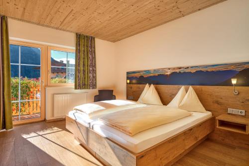 a bedroom with a large bed and a large window at Landhotel Kirchenwirt in Unken