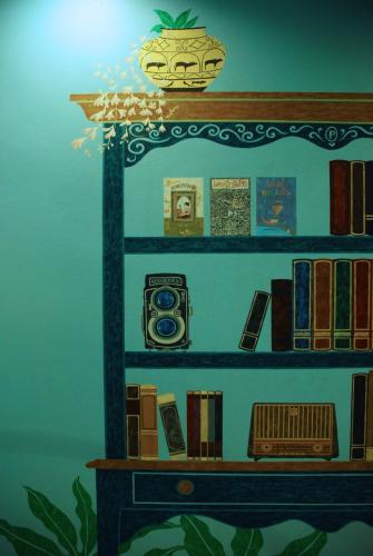 a shelf with books and a clock on it at Pupiang po Da Arte Resort in Dan Sai