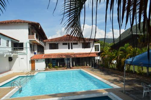 a villa with a swimming pool in front of a house at Hotel Campestre La Ribera del Fonce in San Gil