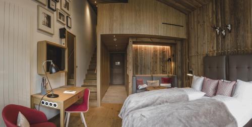 a bedroom with two beds and a desk and a chair at Löwen Hotel Montafon in Schruns