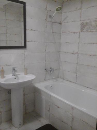 een witte badkamer met een wastafel, een bad en een wastafel bij Нова квартира in Ivano-Frankivsʼk