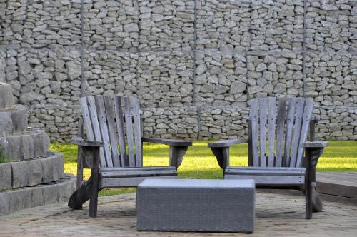 two wooden chairs sitting in front of a stone wall at Slaley Country House in Stellenbosch