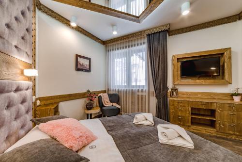 a bedroom with a large bed and a television at Willa Roztoka & SPA - idealne miejsce dla Twojej rodziny in Bukowina Tatrzańska