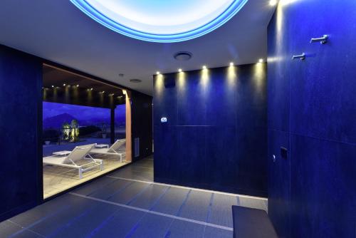 a room with a blue wall with a table and chairs at Hotel Parco Degli Aromi Resort & SPA in Valderice