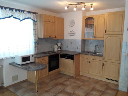 a kitchen with wooden cabinets and a sink and a microwave at Ferienwohnung Kupfer in Göstling an der Ybbs