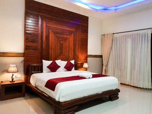 ein Schlafzimmer mit einem großen Bett mit einem hölzernen Kopfteil in der Unterkunft Ogix Cliff Paradise in Nusa Penida