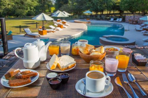 a table with breakfast foods and drinks next to a pool at Ayres del Champaqui Hotel Boutique Experiencial & Spa in Villa General Belgrano