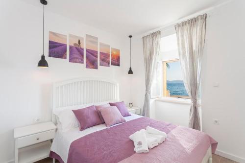 Schlafzimmer mit einem Bett mit rosa und lila Kissen in der Unterkunft Apartmani Antiqua in Živogošće