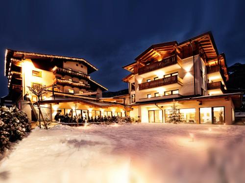 a large building in the snow at night at Hotel Theresia in Ramsau im Zillertal