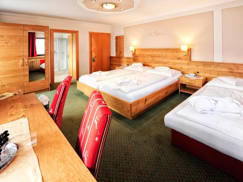 a hotel room with three beds and tables and chairs at Hotel Theresia in Ramsau im Zillertal