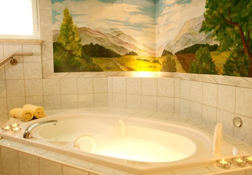 a bath tub in a bathroom with a painting on the wall at Landhotel Bayerwald in Grafling