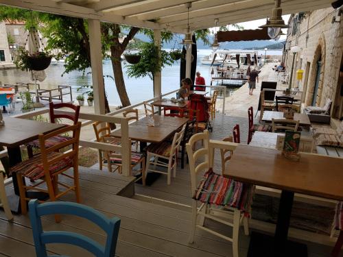 ein Restaurant mit Holztischen und -stühlen und Wasser in der Unterkunft Apartments Orica I in Suđurađ