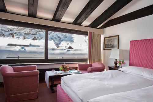 a hotel room with a bed and a large window at Thurnher's Alpenhof in Zürs am Arlberg