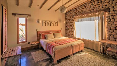 a bedroom with a bed in a room with logs at Casita La Brea in San Pedro de Atacama
