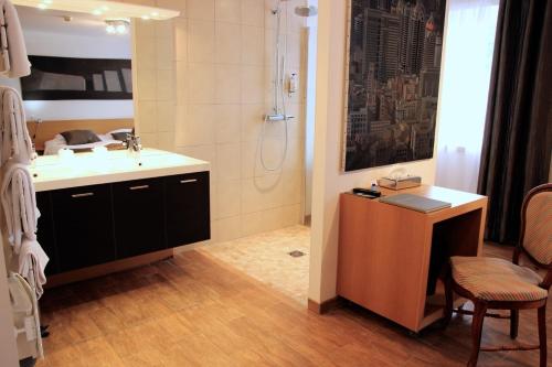 a bathroom with a sink and a shower and a desk at ART Hôtel in Kaysersberg