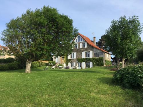 une grande maison avec un arbre dans la cour dans l'établissement Chambres d'hôtes Les 4 Vents Pointe du Hoc - Landing Beaches, à Grandcamp-Maisy