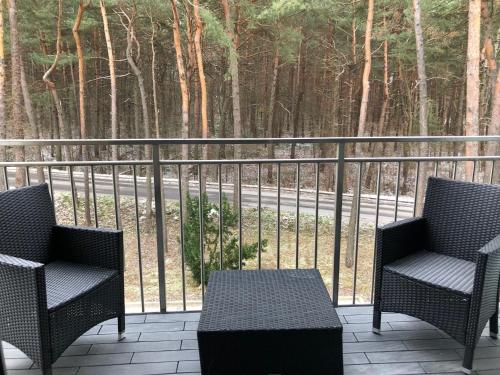 two chairs and a table on a balcony with trees at Family & Business Sauna Apartments No2 Leśny nad Zalewem Cedzyna - 2 Bedroom with Private Sauna, Bath with Hydromassage, Terrace, Parking, Catering Options in Kielce