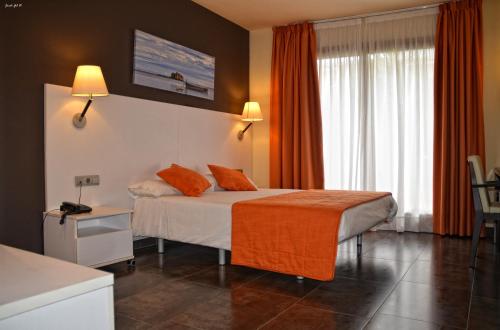 a hotel room with a bed with an orange blanket at Hotel Can Batiste in Sant Carles de la Ràpita