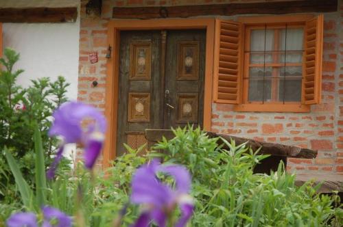 a front door of a house with purple flowers at Múltidéző Porta - Népi Műemlék Házak az Őrségben in Szalafő