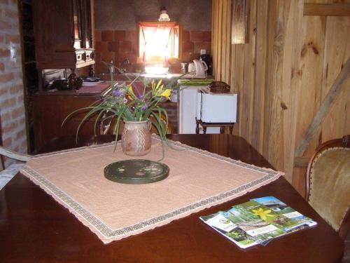 a table with a plate and a vase of flowers on it at Múltidéző Porta - Népi Műemlék Házak az Őrségben in Szalafő