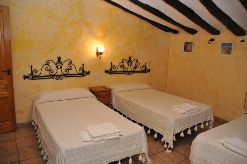 a room with two beds with white sheets at Casa Rural "La Bardena Blanca I " in Arguedas