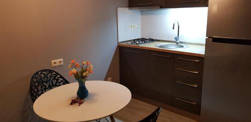 a small kitchen with a table with a vase of flowers on it at Luxury Room in Batumi