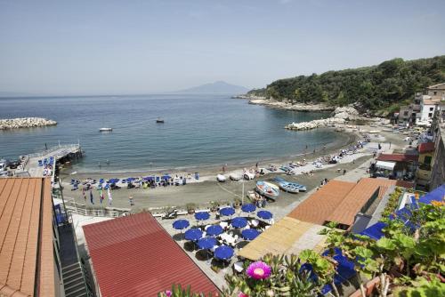 a beach with umbrellas and a crowd of people at Hotel Baia Di Puolo in Massa Lubrense