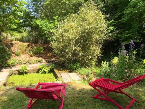 Saint-Quay-PerrosにあるManoir des petites bretonnesの庭の芝生に座る赤い椅子2脚