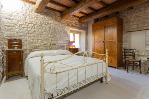 a bedroom with a white bed and a stone wall at Villa Costanzi: Beautiful Rural Apartment! in Sigillo