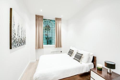 a white bedroom with a bed and a window at Terlon Apartments in Liverpool