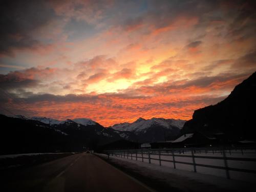 an empty road with a sunset in the mountains at Ferienwohnung Meiringen in Meiringen
