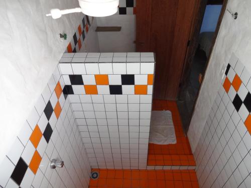 uma casa de banho em azulejo laranja e branco com um WC em Pousada Das Candeias em Carrancas
