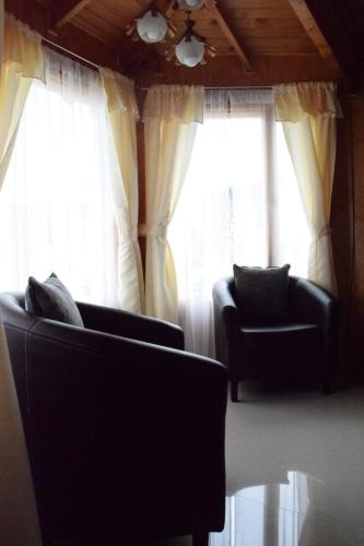 a living room with two chairs and two windows at Paraiso Patagonico in Chaitén