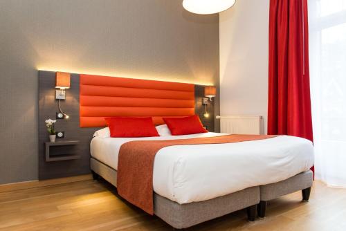 a bedroom with a large bed with an orange headboard at Hôtel Lutétia & Spa in La Baule