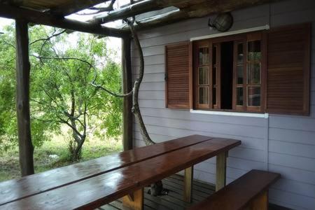 a wooden bench sitting on the porch of a house at AMBRA in Punta Del Diablo