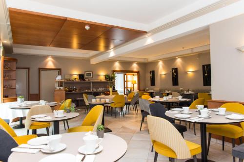 a restaurant with white tables and yellow chairs at Hôtel Lutétia & Spa in La Baule